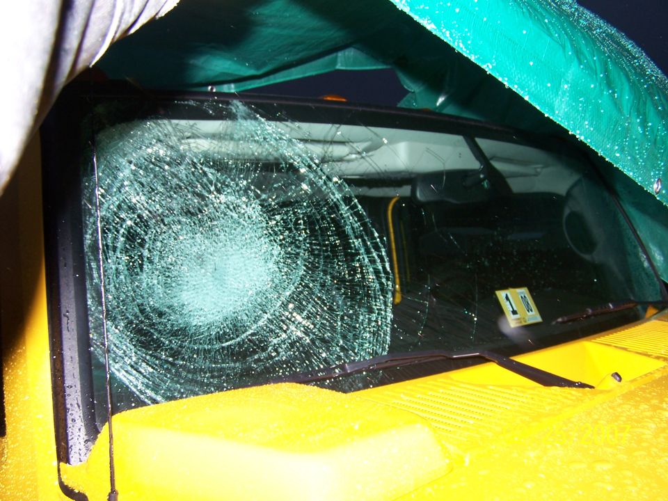 Yellow 2006 Hummer H2 front view, windshield heavily cracked, covered partially by a green tarp