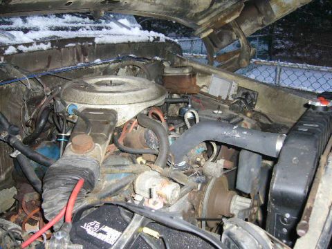 1979 Ford Bronco - The engine bay of a vehicle, with snow visible on the hood hinges and surrounding area. Text from a watermark is visible at the bottom righ…
