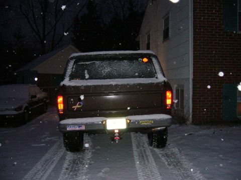 1979 Ford Bronco - A brown Ford Bronco is parked in a snowy driveway at night, with tire tracks visible in the snow.