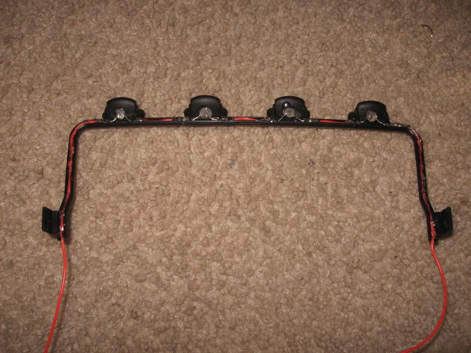 Light bar with four lights and red wiring, mounted on carpet