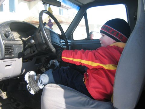 1995 Ford Bronco - Youngster pretends to drive a 1995 Ford Bronco, hands gripping the steering wheel.