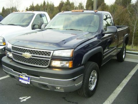 1994 Ford F-150 - A dark blue Chevrolet pickup truck is parked next to a white truck.