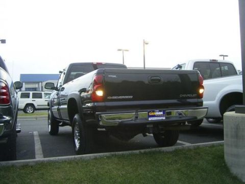 1994 Ford F-150 - Rear view of a black Chevrolet Silverado pickup truck parked in a lot, with a white truck visible behind it.