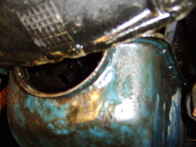 Close-up of greasy engine part with hex bolt in dark cavity