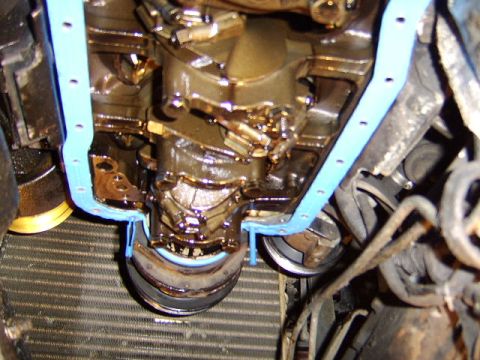 1989 Ford Bronco - Underside engine view during an oil pan gasket job, showing the removed oil pan with a light blue gasket, oil-coated engine block, cranksha…