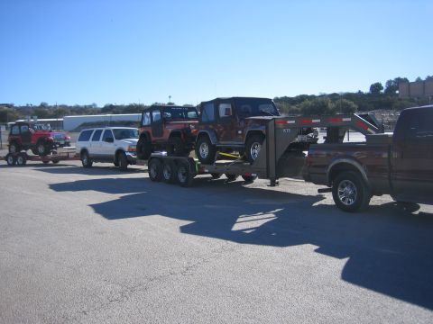 1996 Ford Bronco - A convoy of vehicles, including multiple Jeeps and a white SUV, are loaded onto trailers for transport.