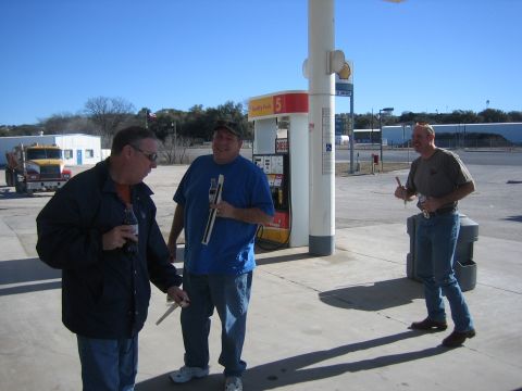 1996 Ford Bronco - Three men converse near a gas pump on a sunny day, with a dump truck in the distance.