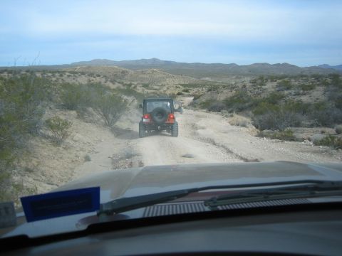 1996 Ford Bronco - Driving off-road through a desert landscape with multiple Jeeps ahead.