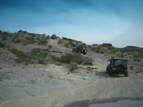 1996 Ford Bronco - Off-road vehicles navigate a challenging, arid terrain on a bright, clear day.