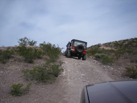 1996 Ford Bronco - Two Jeeps navigate a challenging off-road trail through a dry, brush-covered landscape.