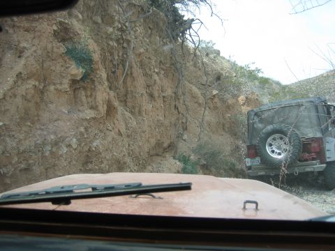 1996 Ford Bronco - Two Jeeps navigate a rough, rocky terrain on an off-road trail.