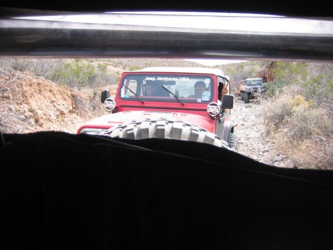 1996 Ford Bronco - A convoy of Jeeps navigates a rough, rocky trail through a dry, arid landscape.