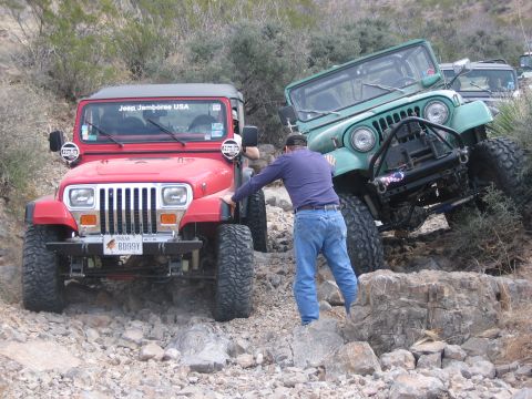 1996 Ford Bronco - Two Jeeps navigate a challenging rocky trail during a Jeep Jamboree USA event.