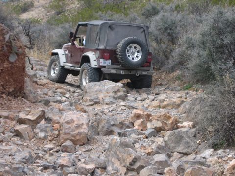 1996 Ford Bronco - Jeep Wrangler TJ tackling a challenging rocky trail in a desert environment.