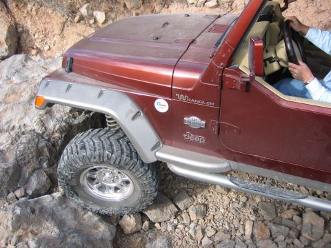 1996 Ford Bronco - Jeep Wrangler TJ model, likely from the 2000s, navigating a rocky trail.