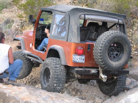 1996 Ford Bronco - Jeep Wrangler TJ navigating a rocky trail with a person in the driver's seat.