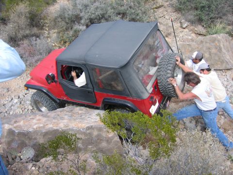 1996 Ford Bronco - Three men attempt to free a red Jeep Wrangler from a difficult rocky terrain.