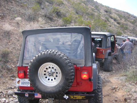 1996 Ford Bronco - A line of Jeep Wranglers navigates a rocky, off-road trail in a desert landscape.
