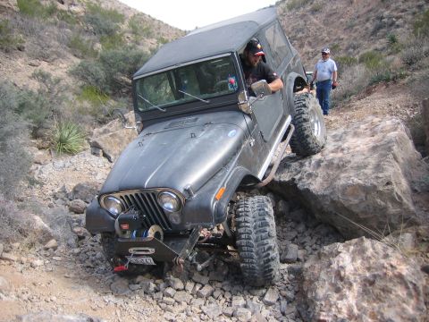 1996 Ford Bronco - Jeep CJ-7 tackling a challenging rocky trail with a driver behind the wheel.