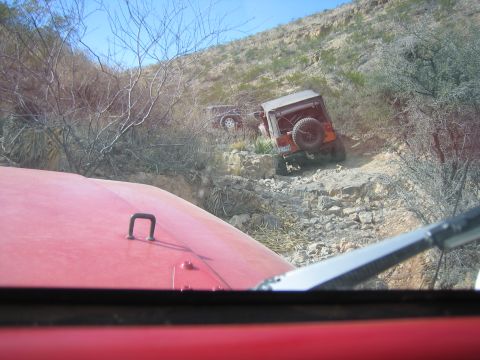 1996 Ford Bronco - Two off-road vehicles navigate a steep, rocky incline under a clear blue sky.