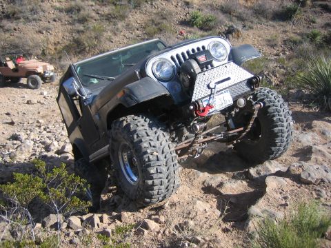 1996 Ford Bronco - Two Jeeps navigate a rocky, off-road trail in a desert environment.