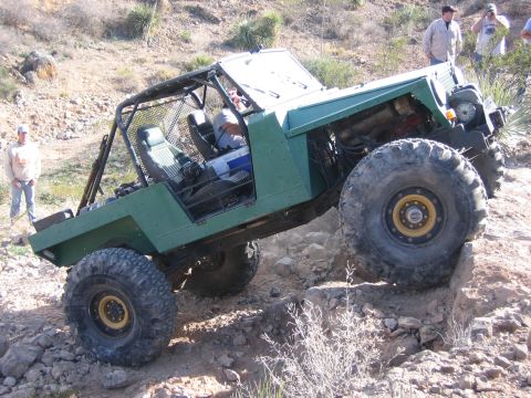1996 Ford Bronco - An off-road vehicle navigates a challenging rocky incline with spectators observing.
