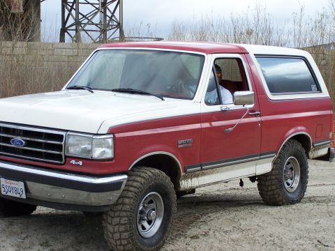 1989 Ford Bronco - This two-tone red and white 1989 Ford Bronco features a lifted suspension and aggressive off-road tires, ready for adventure.