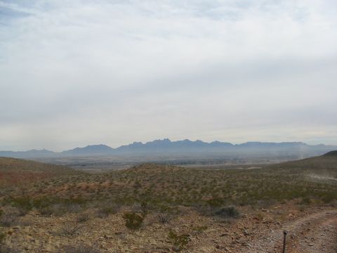 1996 Ford Bronco - A wide view of a dry, arid landscape with rolling hills and a mountain range on the horizon.