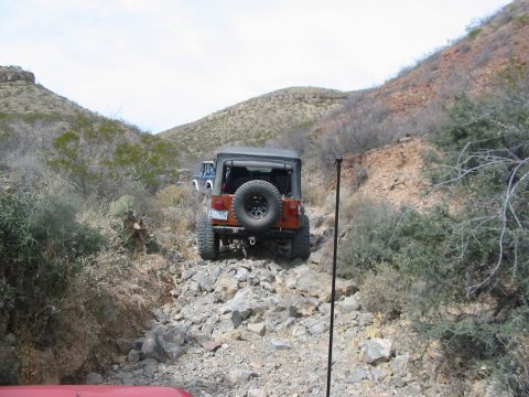 1996 Ford Bronco - Multiple Jeeps navigate a challenging rocky terrain on an off-road trail.