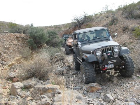 1996 Ford Bronco - A convoy of Jeeps navigates a , off-road path through a dry, arid landscape.