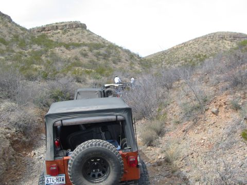 1996 Ford Bronco - Multiple Jeeps navigate a , off-road trail through a dry, hilly landscape.