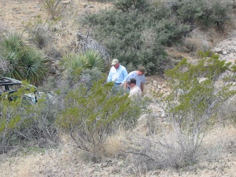 1996 Ford Bronco - Three men examine a partially obscured off-road vehicle in a dry, brushy environment.