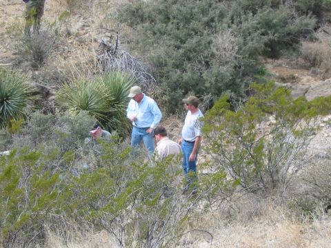 1996 Ford Bronco - Several men are gathered in a natural, arid environment with sparse vegetation.