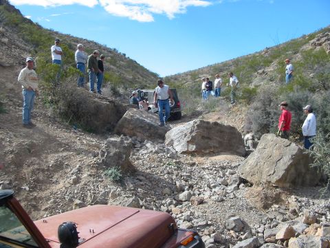 1996 Ford Bronco - A group of people watch as SUVs navigate a challenging rocky terrain in a desert landscape.