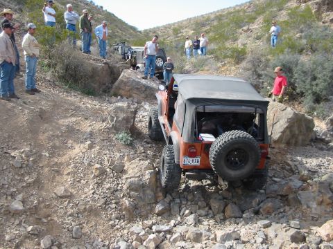 1996 Ford Bronco - Several people watch an orange Jeep Wrangler tackle a difficult rocky trail.