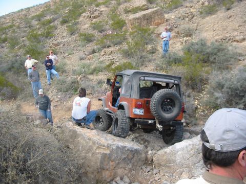 1996 Ford Bronco - Jeep Wrangler tackling a difficult off-road trail with a group of onlookers.
