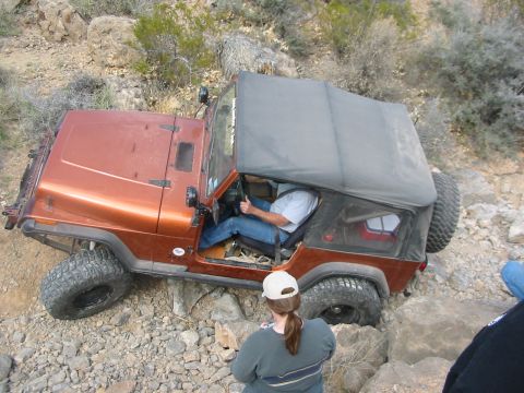 1996 Ford Bronco - A driver navigates a Jeep Wrangler TJ over a challenging, rocky terrain.