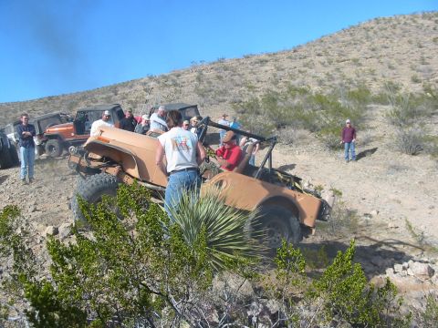 1996 Ford Bronco - Off-road vehicles and spectators gather on a desert hillside under a clear blue sky.