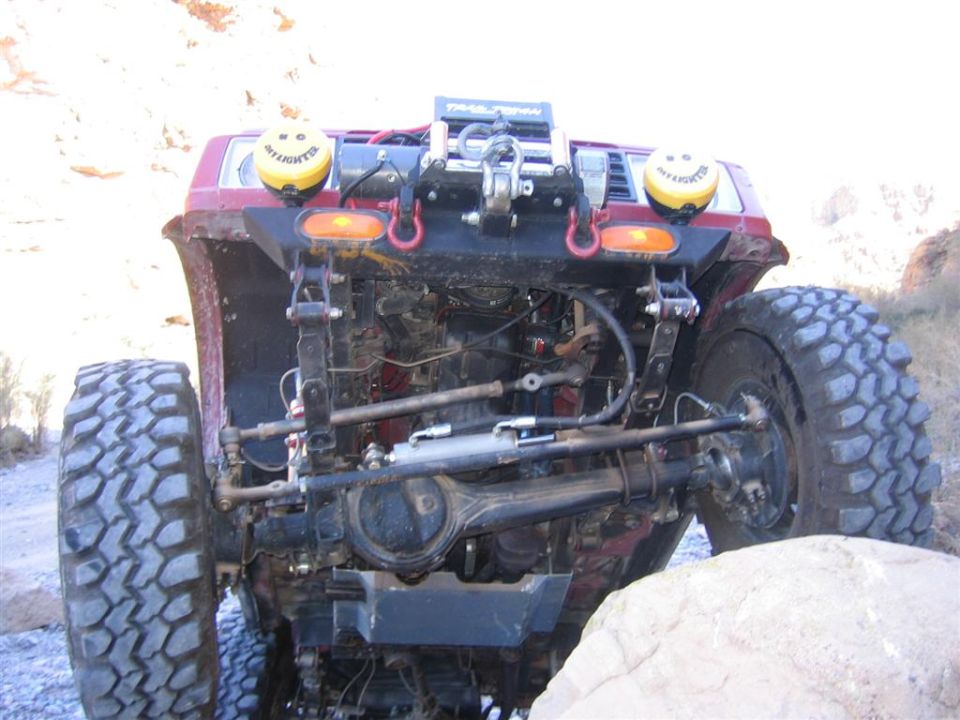 Red off-road vehicle front axle and suspension with large tires and winch