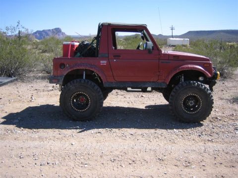 1987 Suzuki Samurai - Modified 1987 Suzuki Samurai parked in a desert landscape with mountains in the background.