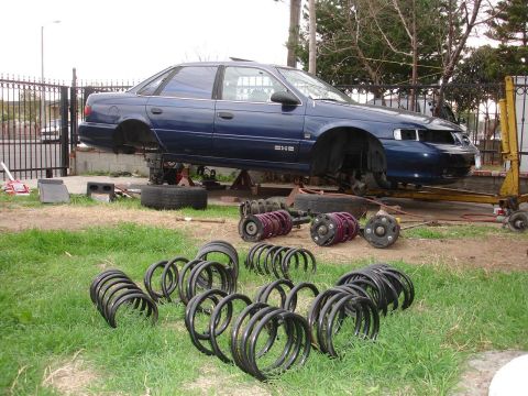 1992 Ford Taurus - A 1992 Ford Taurus is raised on jack stands with numerous suspension springs and struts removed and placed on the lawn.