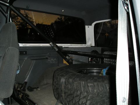 1993 Ford Bronco - The interior of the vehicle shows a spare tire secured in the cargo area, along with a roll cage and audio equipment.