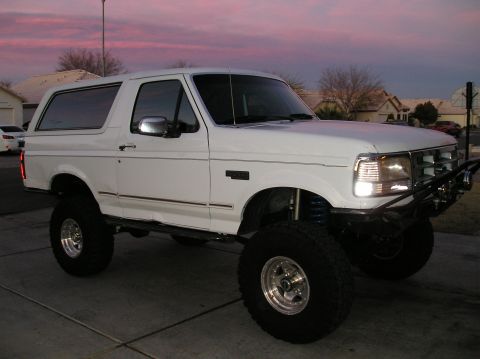 1993 Ford Bronco - White 1993 Ford Bronco lifted with aftermarket bumper, parked outside at dusk.