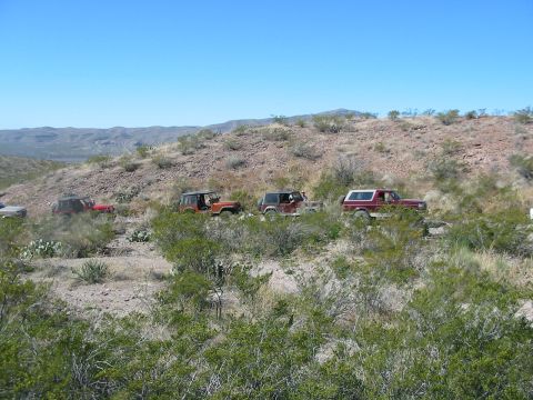 1996 Ford Bronco - Multiple SUVs navigate a desert trail, with mountains in the background.