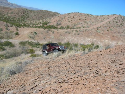 1996 Ford Bronco - Jeep Wrangler navigates a challenging rocky terrain on a sunny day.
