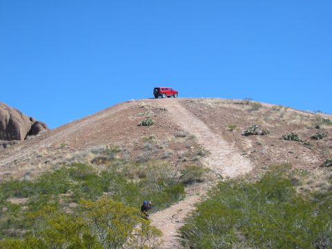 1996 Ford Bronco - Red SUV parked on a hilltop overlooking a desert landscape.