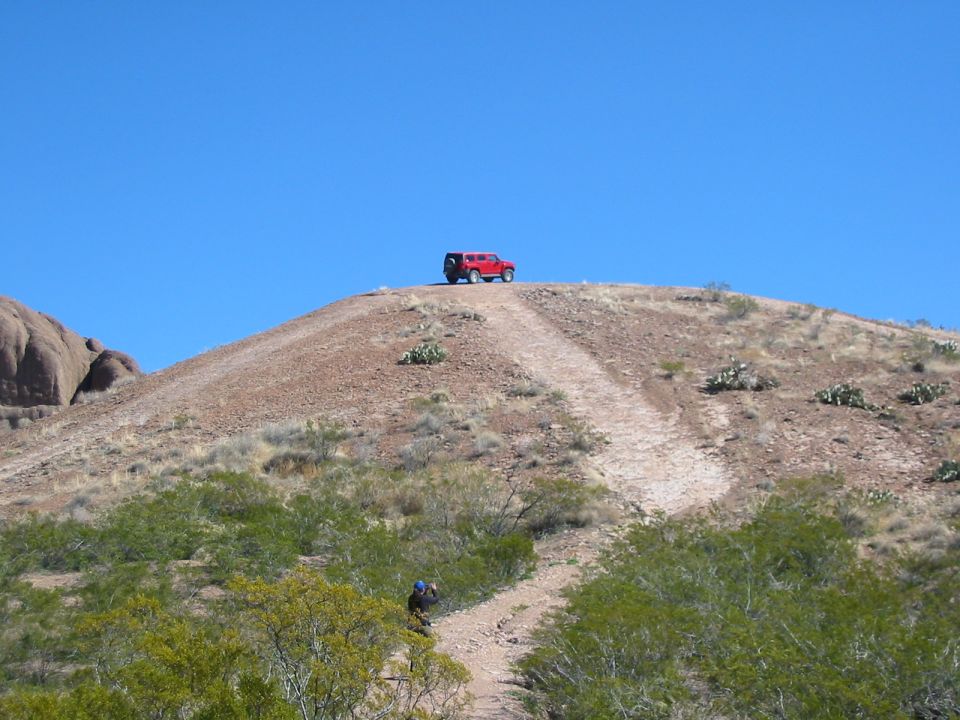 Red SUV parked on top of a hill with a dirt road leading up to it