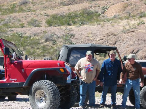1996 Ford Bronco - Three men stand next to several Jeep Wranglers in a rocky, arid landscape.