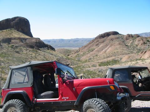 1996 Ford Bronco - Two Jeep Wranglers are parked in a rocky, arid environment under a clear blue sky.