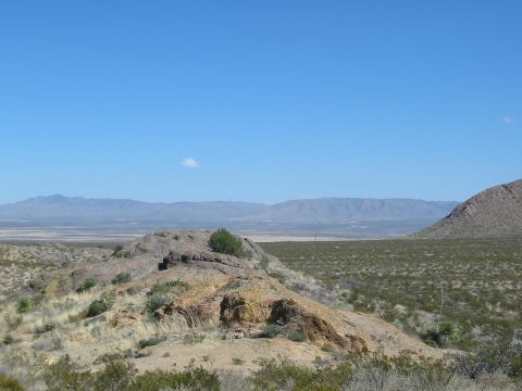1996 Ford Bronco - A wide view of a desert landscape rolling hills, sparse vegetation, and distant mountain ranges under a bright blue sky.
